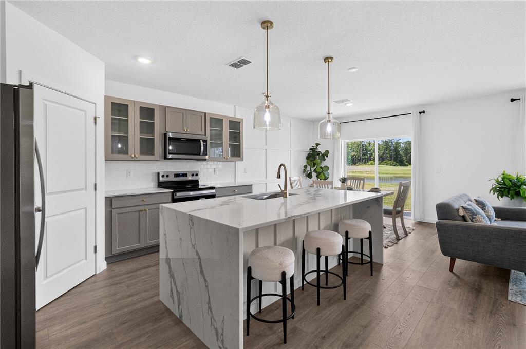 A kitchen with gray cabinets, a marble-topped island, and a view of a pond outside — 1037 CHAMPION RDG DRIVE, DAYTONA BEACH, FL