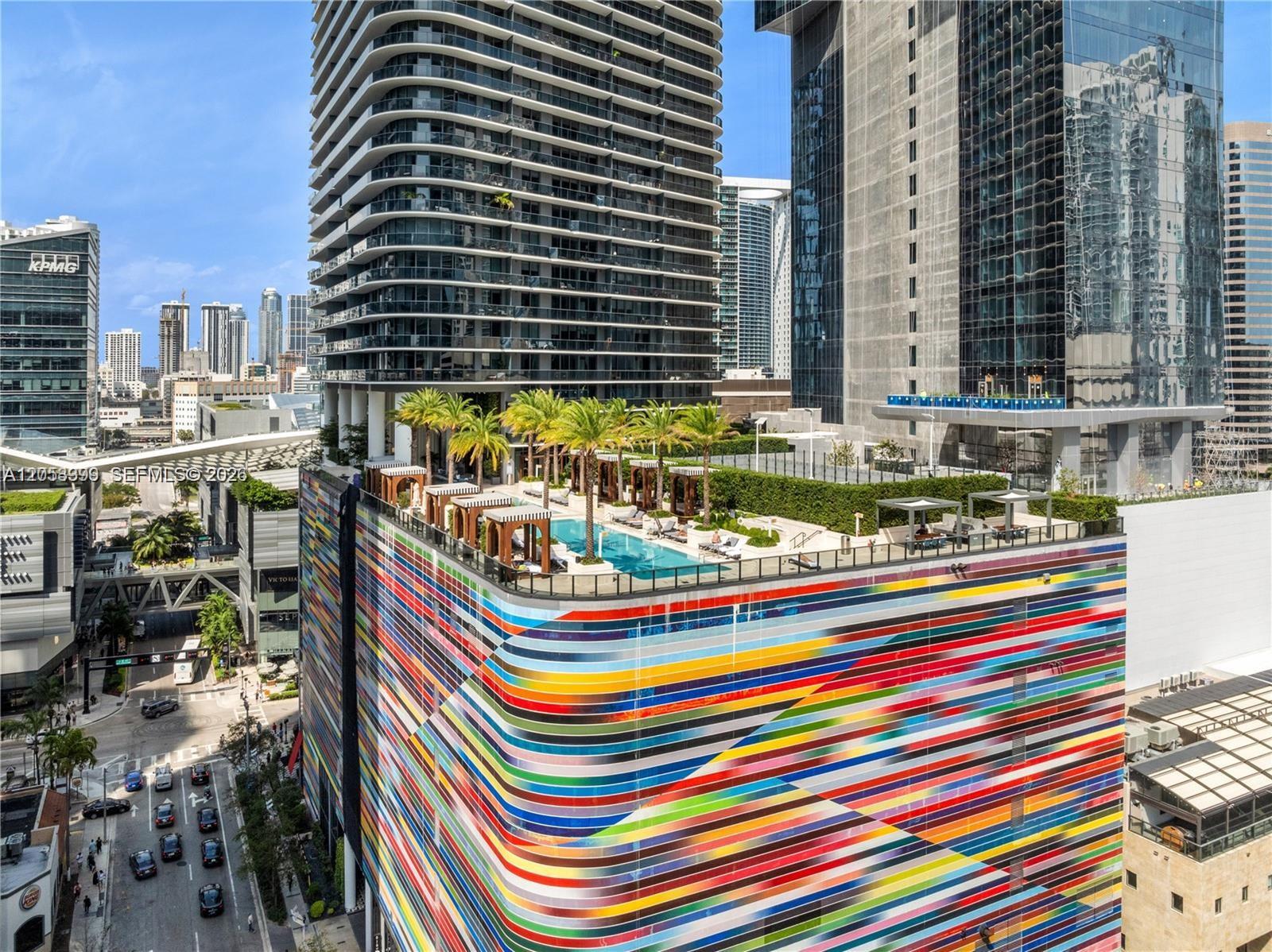 An aerial view shows a colorful, striped building exterior with a rooftop pool and palm trees — 801 S Miami Ave # 3006, Miami FL 33130, MIAMI, FL