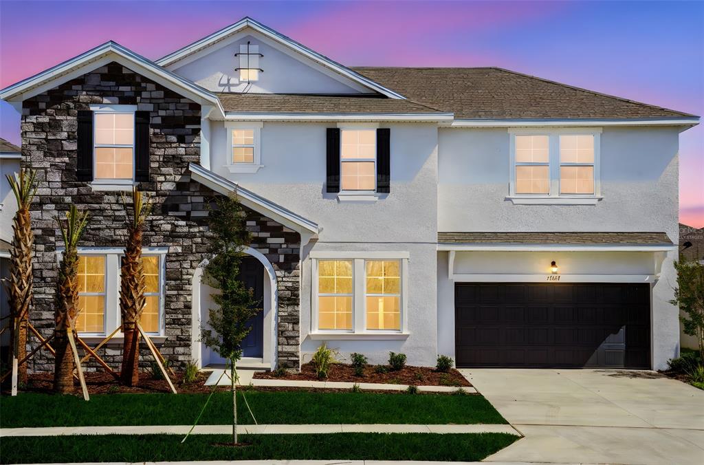 A two-story house with a stone facade, white stucco, and a two-car garage — 17417 VALLEYWOOD PARKWAY, LAND O LAKES, FL