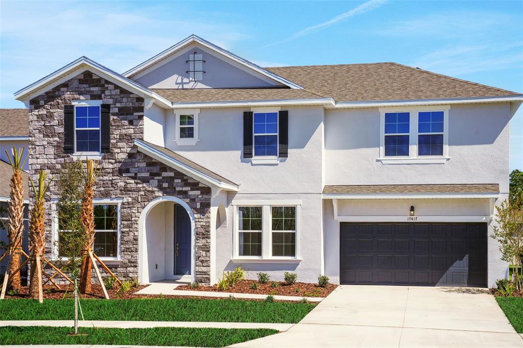 A two-story suburban house features a stone facade, stucco exterior, and a two-car garage — 17417 VALLEYWOOD PARKWAY, LAND O LAKES, FL