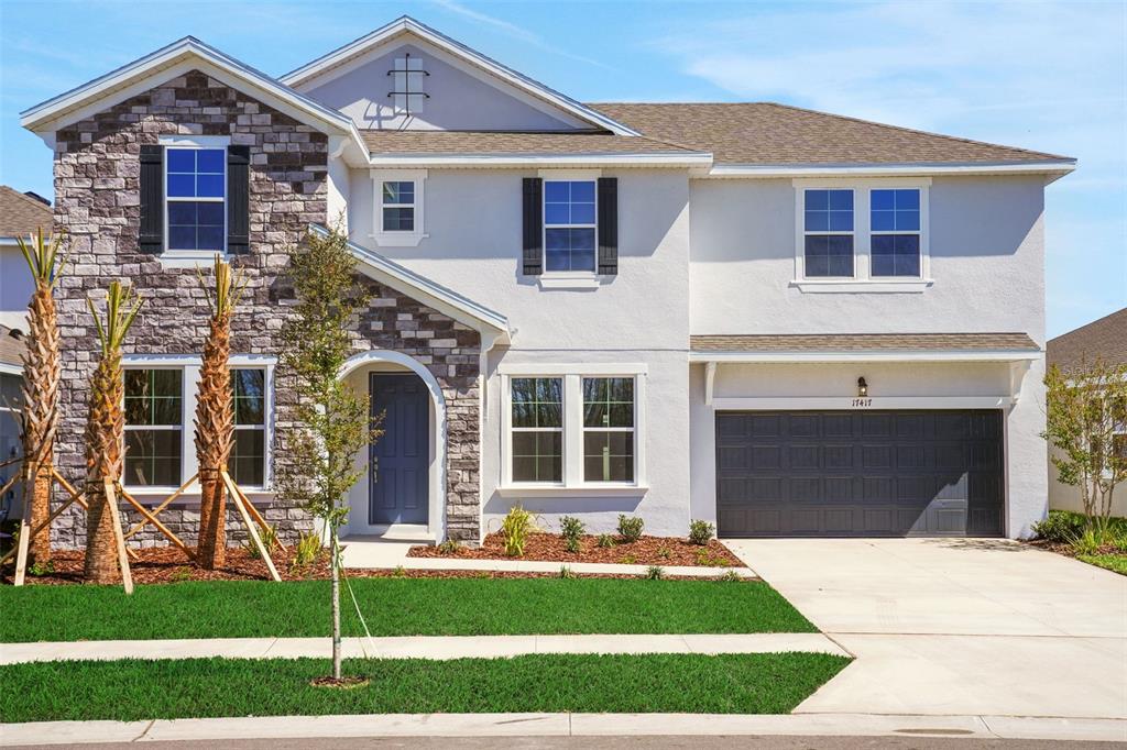 A two-story suburban house features a stone facade, white stucco, and an attached two-car garage — 17417 VALLEYWOOD PARKWAY, LAND O LAKES, FL