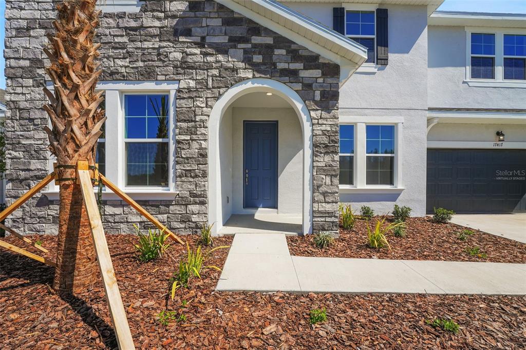 The exterior of a two-story house features a stone facade, a blue front door, and a garage — 17417 VALLEYWOOD PARKWAY, LAND O LAKES, FL