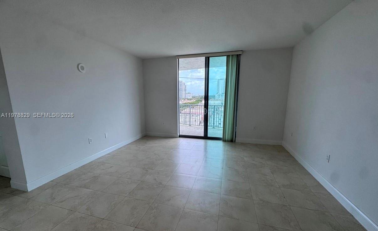 An empty room with light tile flooring features a sliding glass door leading to a balcony — 140 S Dixie Hwy # 719, Hollywood FL 33020, HOLLYWOOD, FL