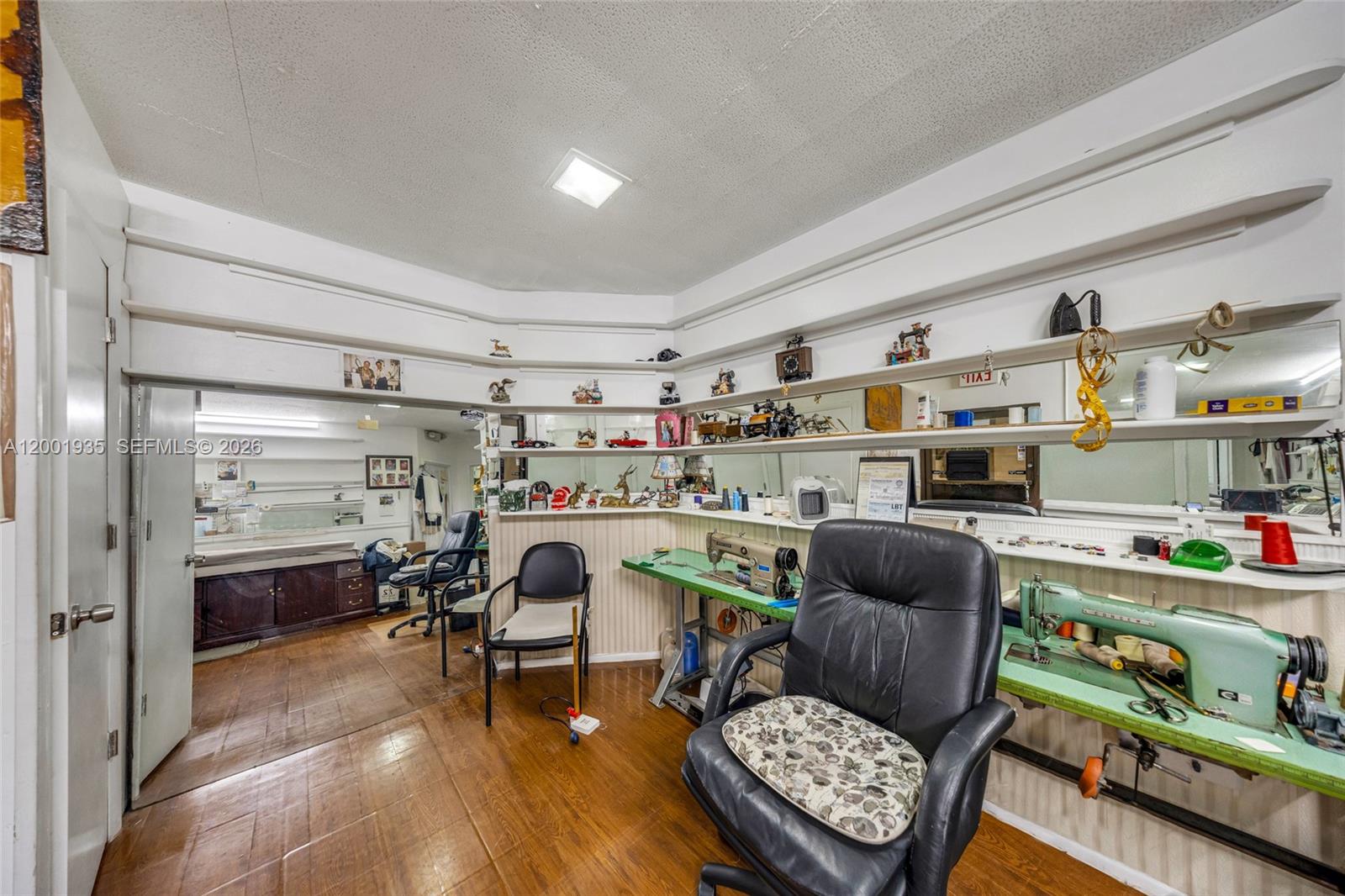 A sewing room with two industrial sewing machines, black office chairs, and tiered wall shelving — 5401 Collins Ave # 9, Miami Beach FL 33140, MIAMI BEACH, FL