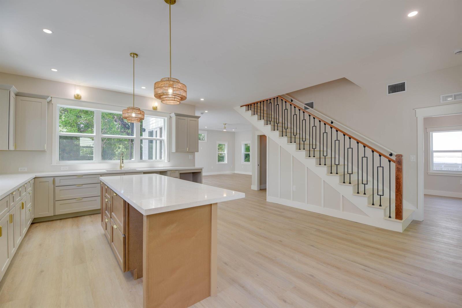 A kitchen with a central island and light wood floors sits beside a staircase — 1316 Royal Street # 6, Key West FL 33040, KEY WEST, FL