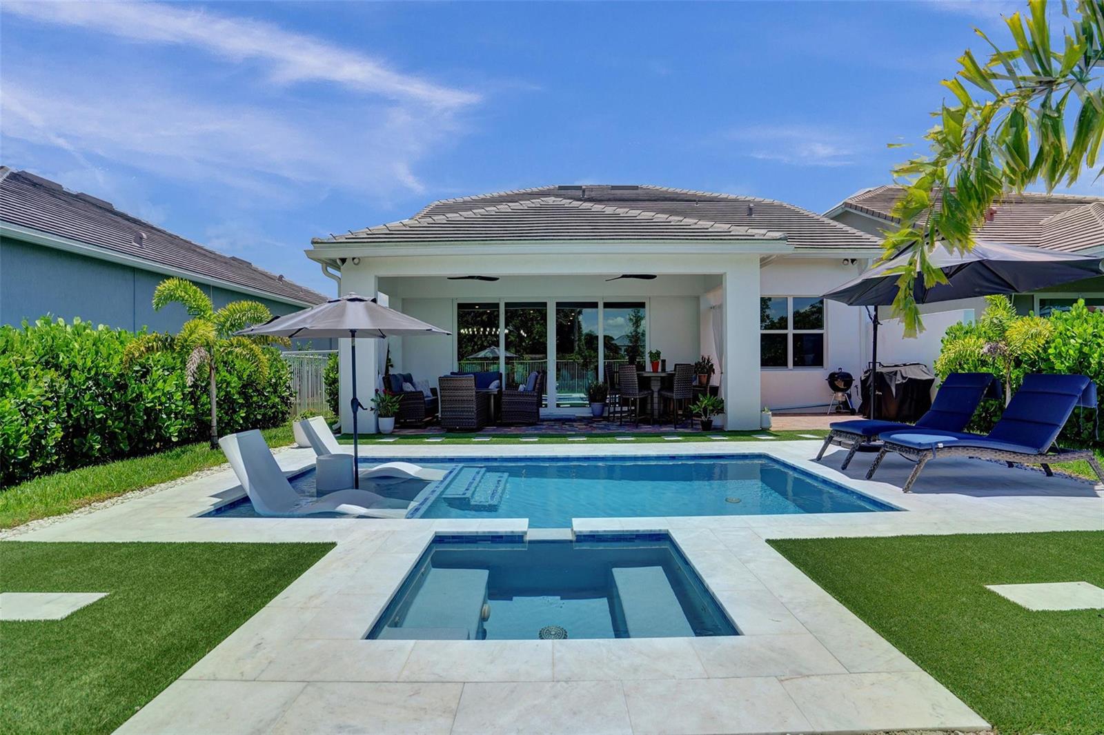 A backyard features a swimming pool, a spa, lounge chairs, and a covered patio area — 9621 Mosler Trail, Lake Worth FL 33467, LAKE WORTH, FL