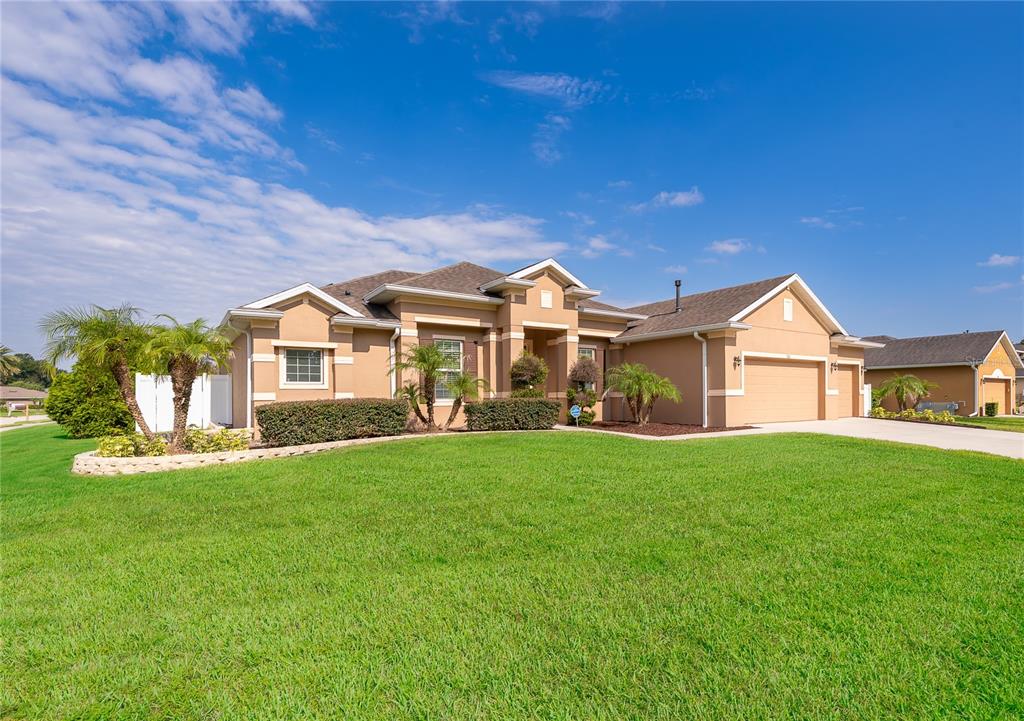 A single-story tan stucco house with a shingled roof and a large front lawn — 700 ELKHORN FERN LANE, DELAND, FL
