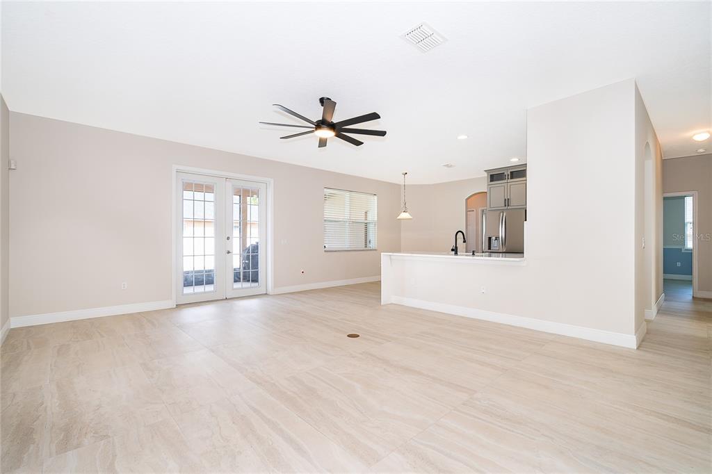 An open-concept living area features light-colored tile flooring, a ceiling fan, and a kitchen island — 700 ELKHORN FERN LANE, DELAND, FL