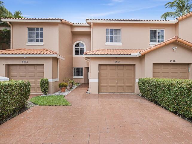 A multi-unit residential building with three garage doors and tan stucco exterior walls — 8596 Jade Drive, Tamarac FL 33321, TAMARAC, FL
