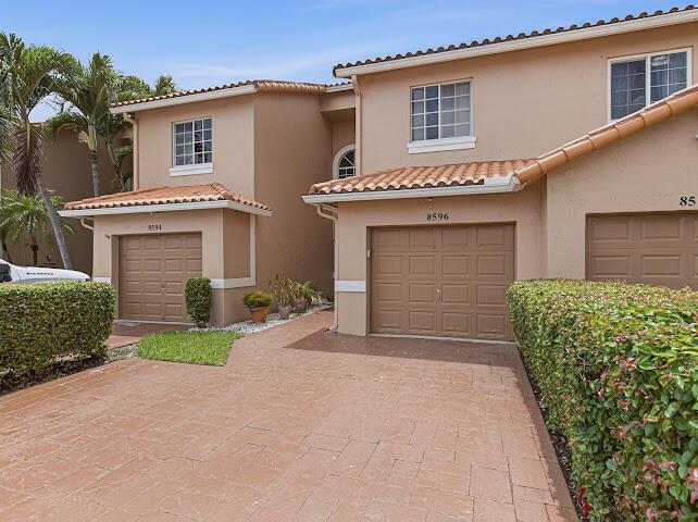 A view of two tan townhouses with brown garage doors and a paved driveway — 8596 Jade Drive, Tamarac FL 33321, TAMARAC, FL