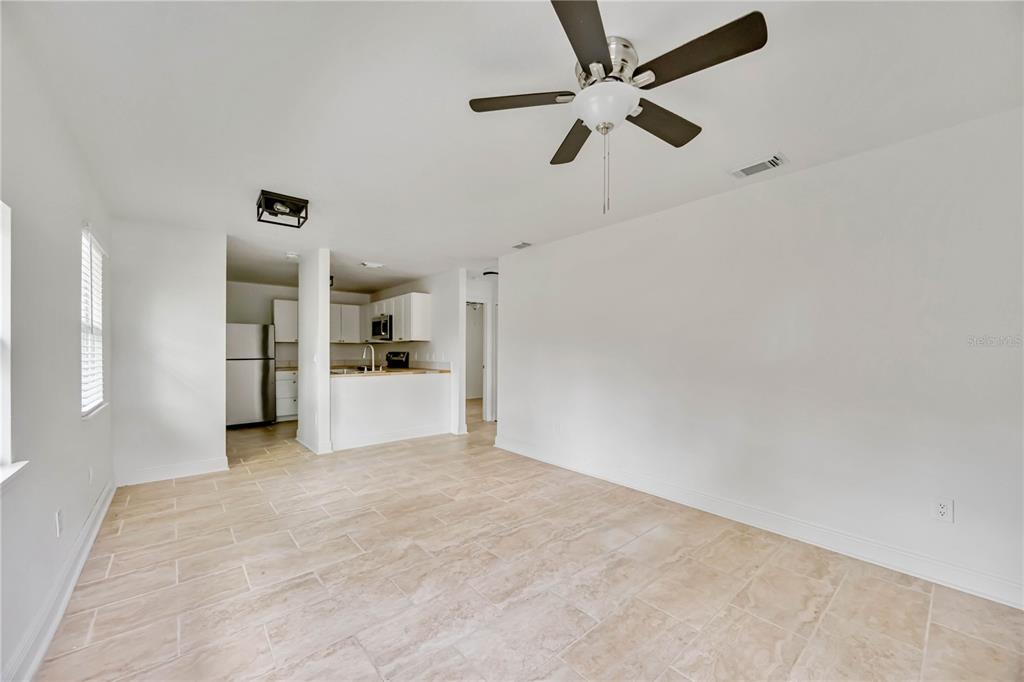 A living room with tile flooring and a ceiling fan opens to a kitchen area — 5433 579 HIGHWAY UNIT A, SEFFNER, FL