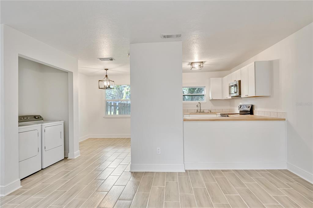 A view of a kitchen and laundry area with light wood-look tile flooring — 5433 579 HIGHWAY UNIT A, SEFFNER, FL