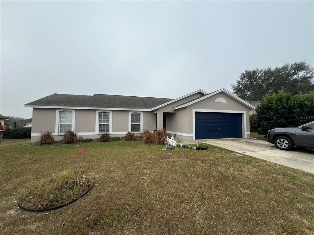 A single-story house with a beige exterior, a dark blue garage door, and a driveway — 3875 HORIZON HILL DRIVE, LAKELAND, FL
