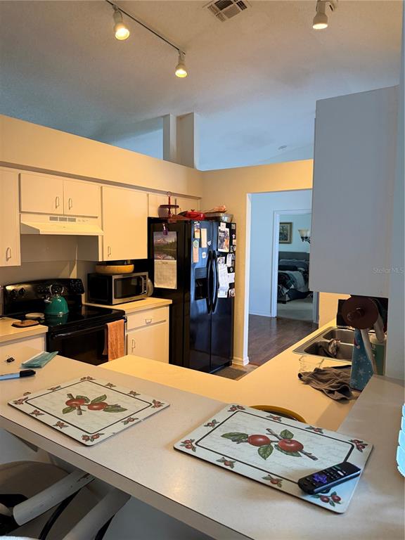 A kitchen features white cabinets, a black refrigerator, a stove, and a breakfast bar — 3875 HORIZON HILL DRIVE, LAKELAND, FL