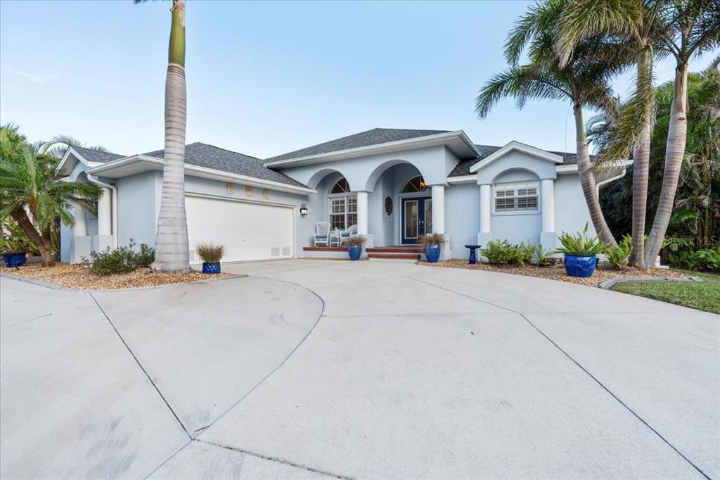 A light blue single-story house with a concrete driveway and palm trees in the front — 1091 ROTONDA CIRCLE, ROTONDA WEST, FL