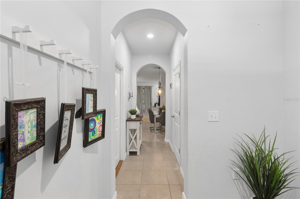 A hallway with arched entryways, tiled flooring, and framed artwork hanging on the left wall — 417 NEWMONT CIRCLE, RUSKIN, FL
