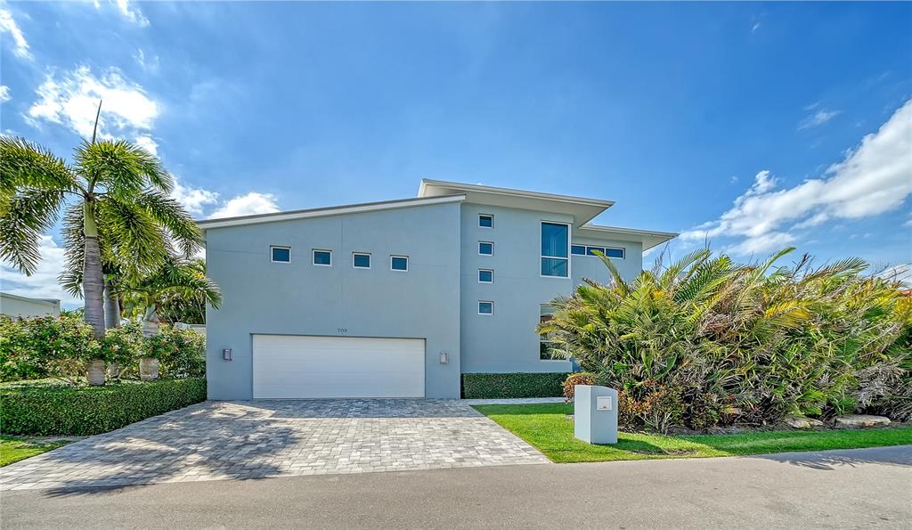 A two-story light blue house features a two-car garage and palm trees in the yard — 705 JUNGLE QUEEN WAY, LONGBOAT KEY, FL