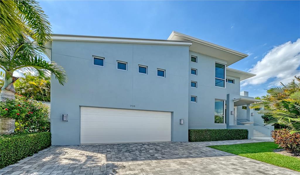 A modern, light blue two-story house features a large garage and a paved driveway — 705 JUNGLE QUEEN WAY, LONGBOAT KEY, FL