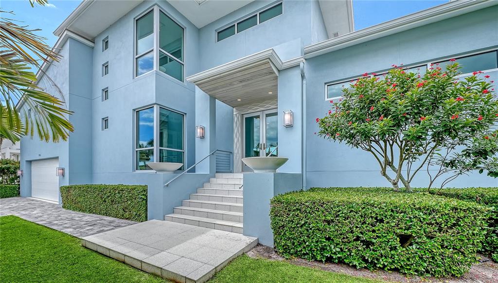 A light blue two-story house features a front entrance with stairs and manicured hedges — 705 JUNGLE QUEEN WAY, LONGBOAT KEY, FL