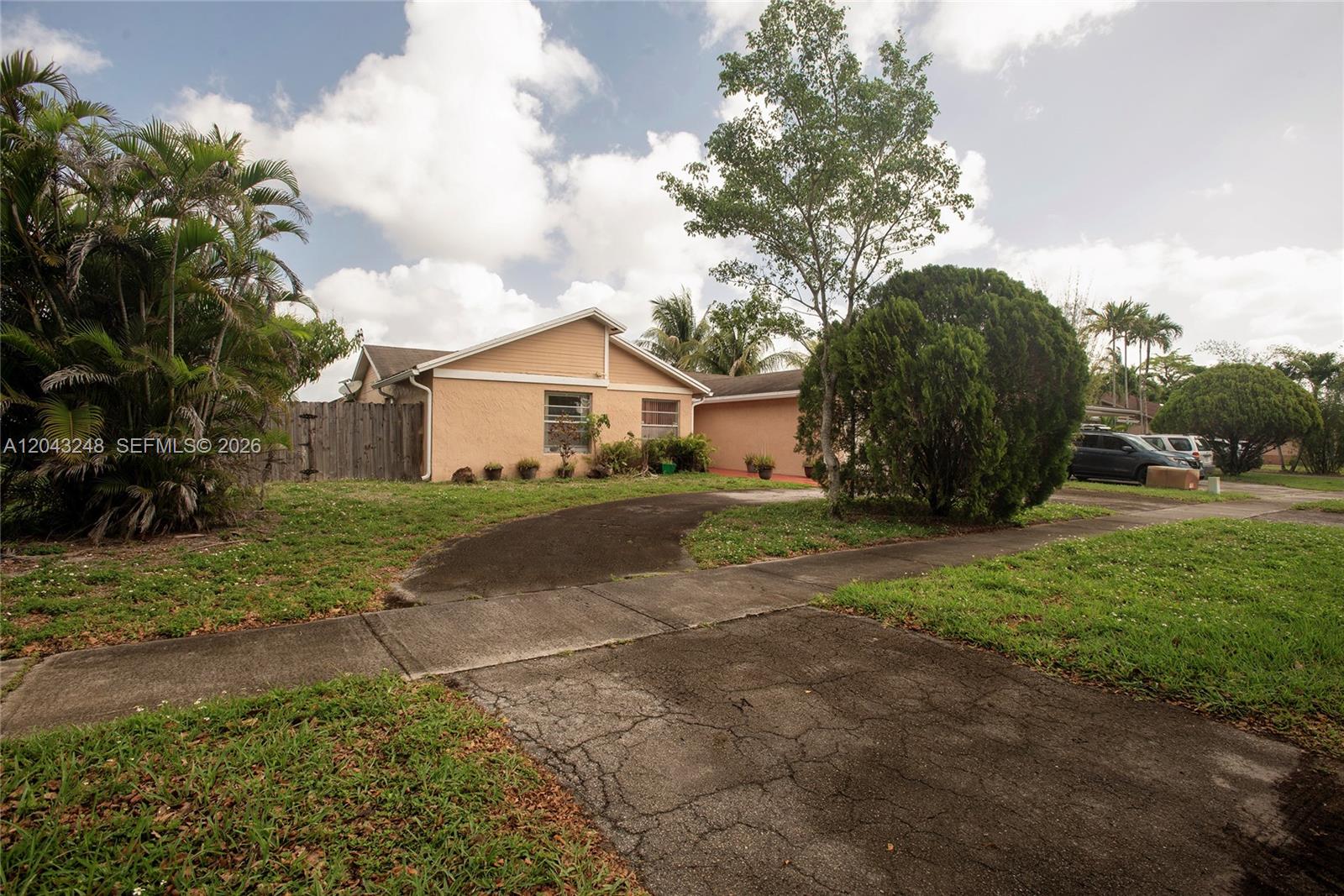 A single-story house with a tan exterior, a curved driveway, and a large front yard — 5889 NW 198th Ter, Hialeah FL 33015, HIALEAH, FL