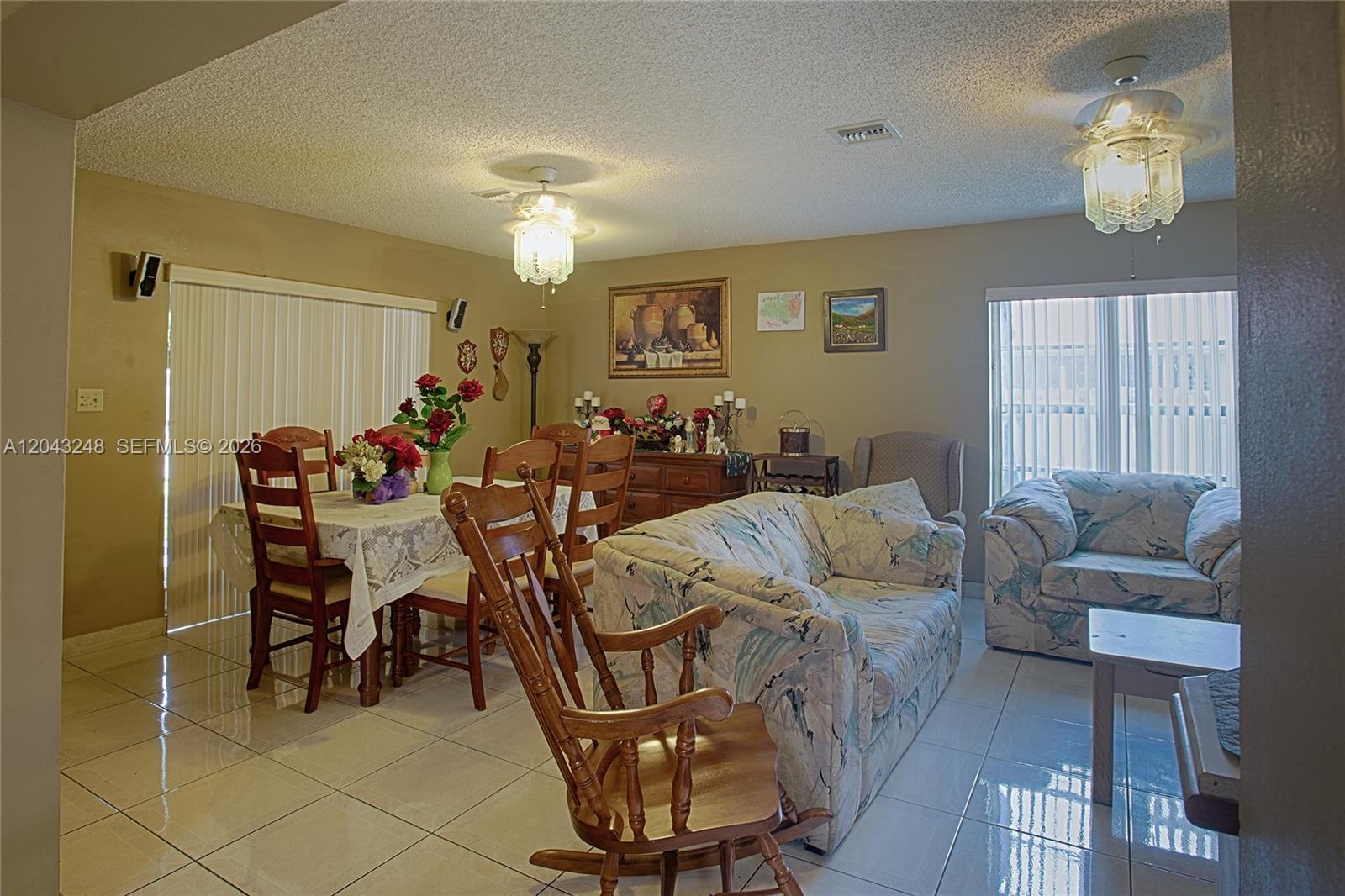 A living and dining room area features tile flooring, two ceiling fans, and patterned furniture — 5889 NW 198th Ter, Hialeah FL 33015, HIALEAH, FL
