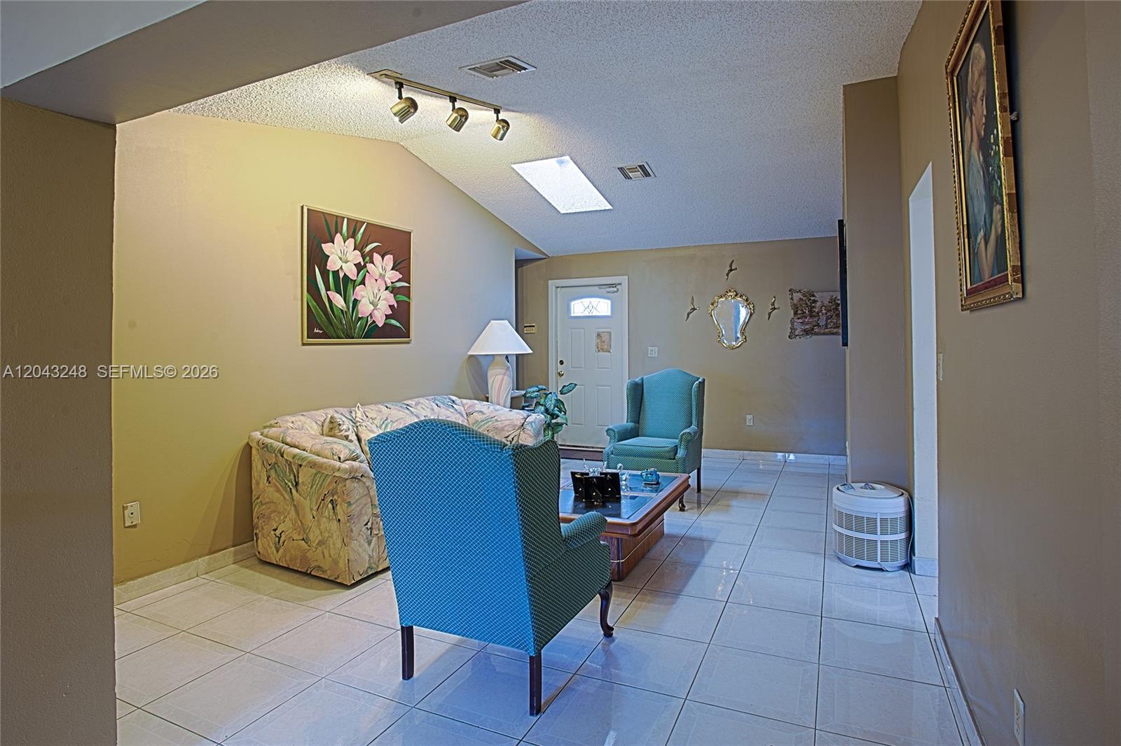 A living room features a vaulted ceiling, tiled floors, a sofa, and two armchairs — 5889 NW 198th Ter, Hialeah FL 33015, HIALEAH, FL