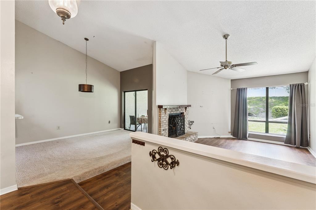 A split-level living area features carpeted and wood-look flooring, a brick fireplace, and vaulted ceilings — 145 OLIVE TREE CIRCLE UNIT 145, ALTAMONTE SPRINGS, FL