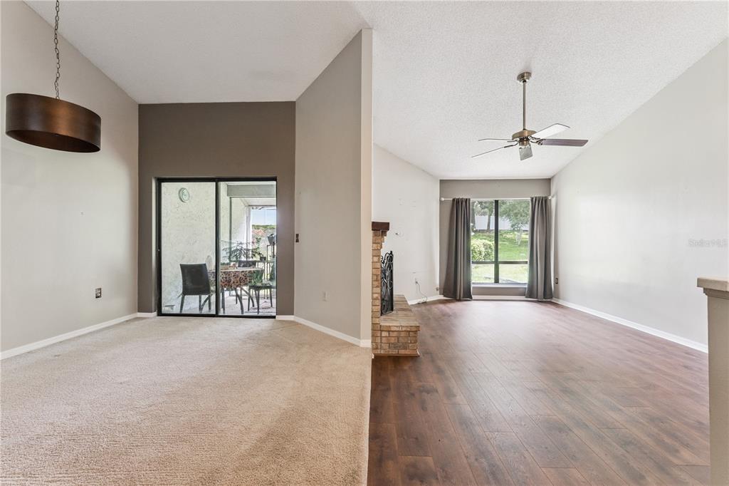 A living room with wood-look flooring and an adjacent carpeted dining area with sliding doors — 145 OLIVE TREE CIRCLE UNIT 145, ALTAMONTE SPRINGS, FL