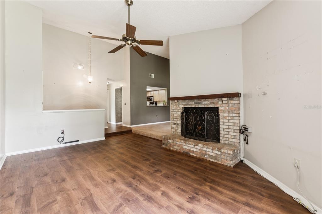 A living room features wood-look flooring, a brick fireplace, and a ceiling fan — 145 OLIVE TREE CIRCLE UNIT 145, ALTAMONTE SPRINGS, FL