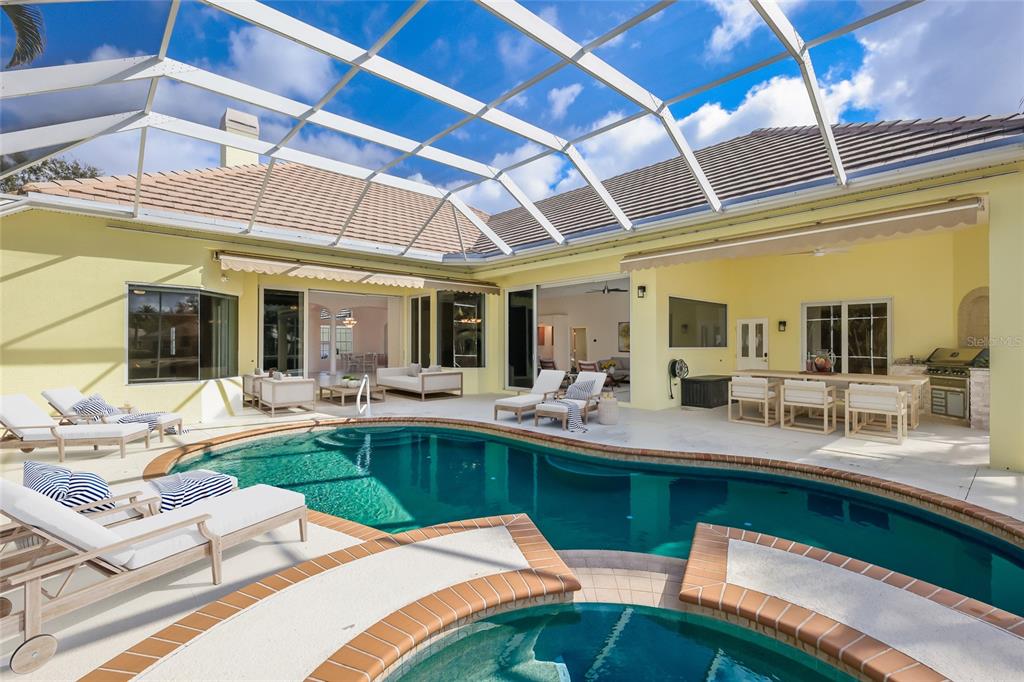 A swimming pool and hot tub sit on a patio enclosed by a screened lanai — 7908 WARWICK GARDENS LANE, UNIVERSITY PARK, FL