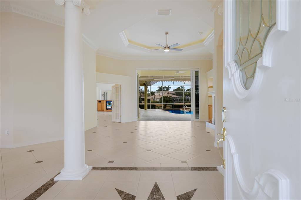 An entryway with a white column leads to a living area with a pool view — 7908 WARWICK GARDENS LANE, UNIVERSITY PARK, FL