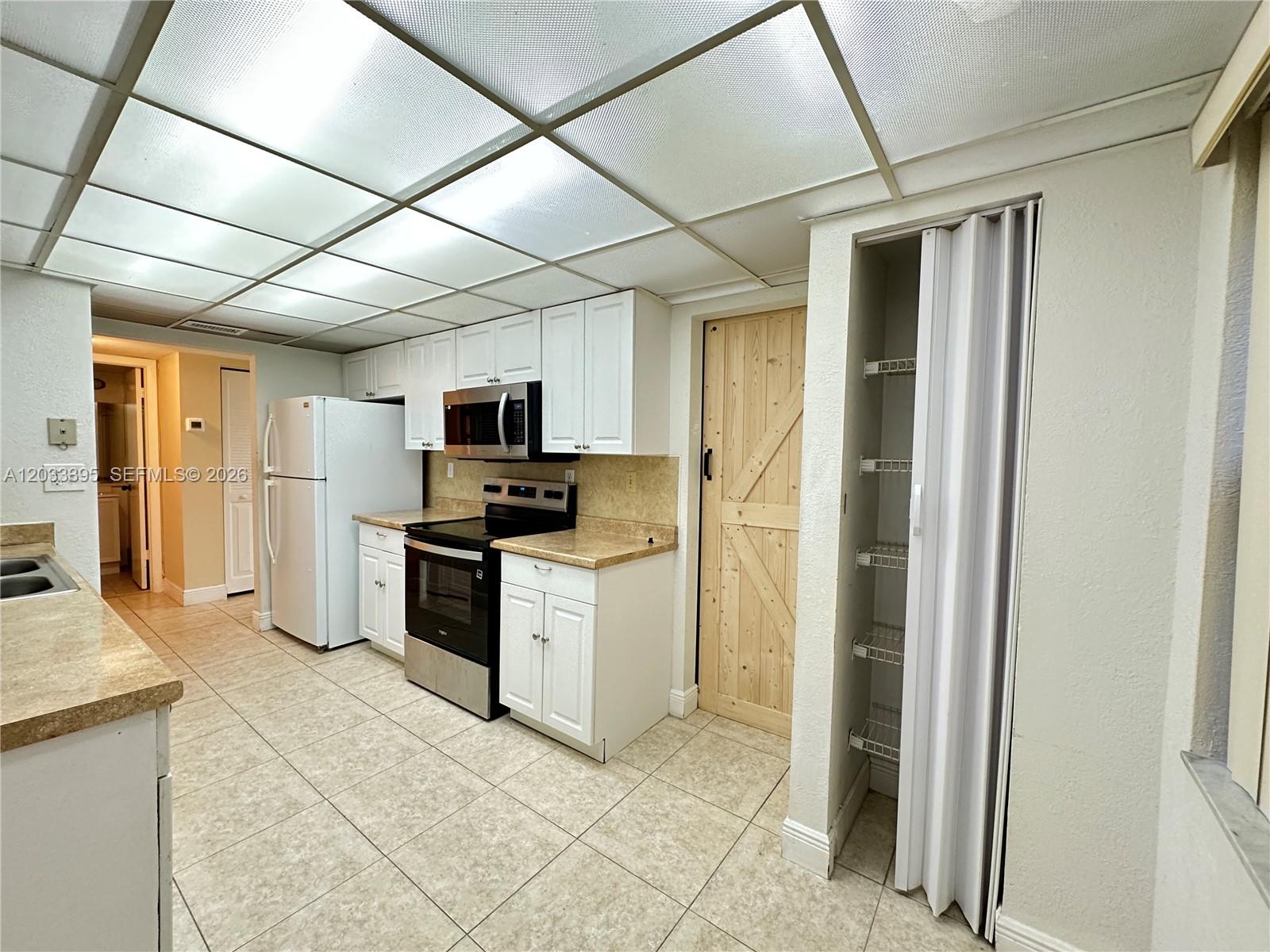 A kitchen features white cabinets, stainless steel appliances, a pantry, and a drop ceiling — 400 Commodore Dr # 308, Plantation FL 33325, PLANTATION, FL