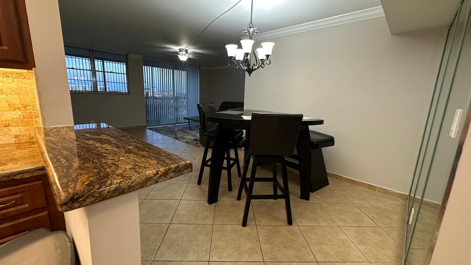 A dining area features a dark wood table, matching chairs, and tile flooring near a kitchen — 3300 W Rolling Hills Circle # 708, Davie FL 33328, DAVIE, FL