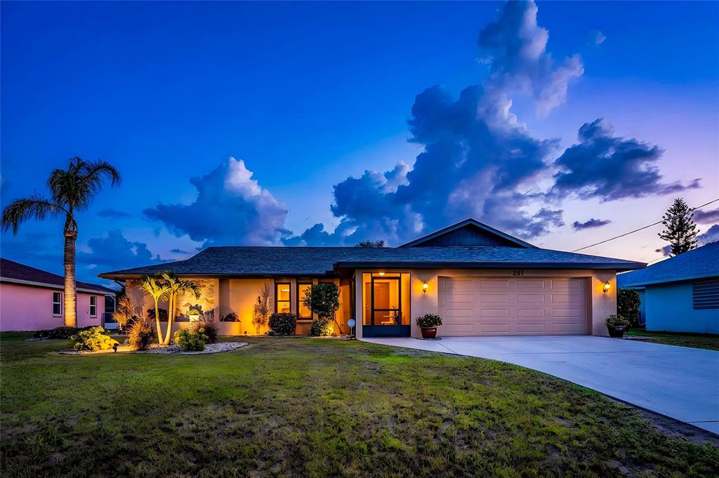 A single-story house with a two-car garage and a screened entryway at twilight — 255 MARK TWAIN LANE, ROTONDA WEST, FL