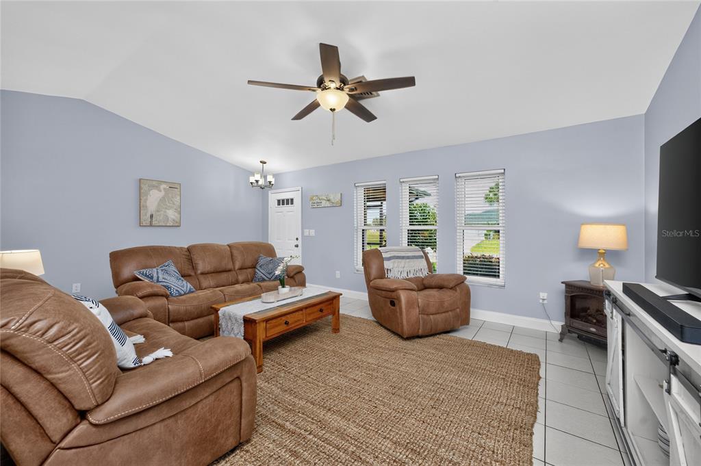 A living room features light blue walls, brown leather furniture, and a large area rug — 255 MARK TWAIN LANE, ROTONDA WEST, FL