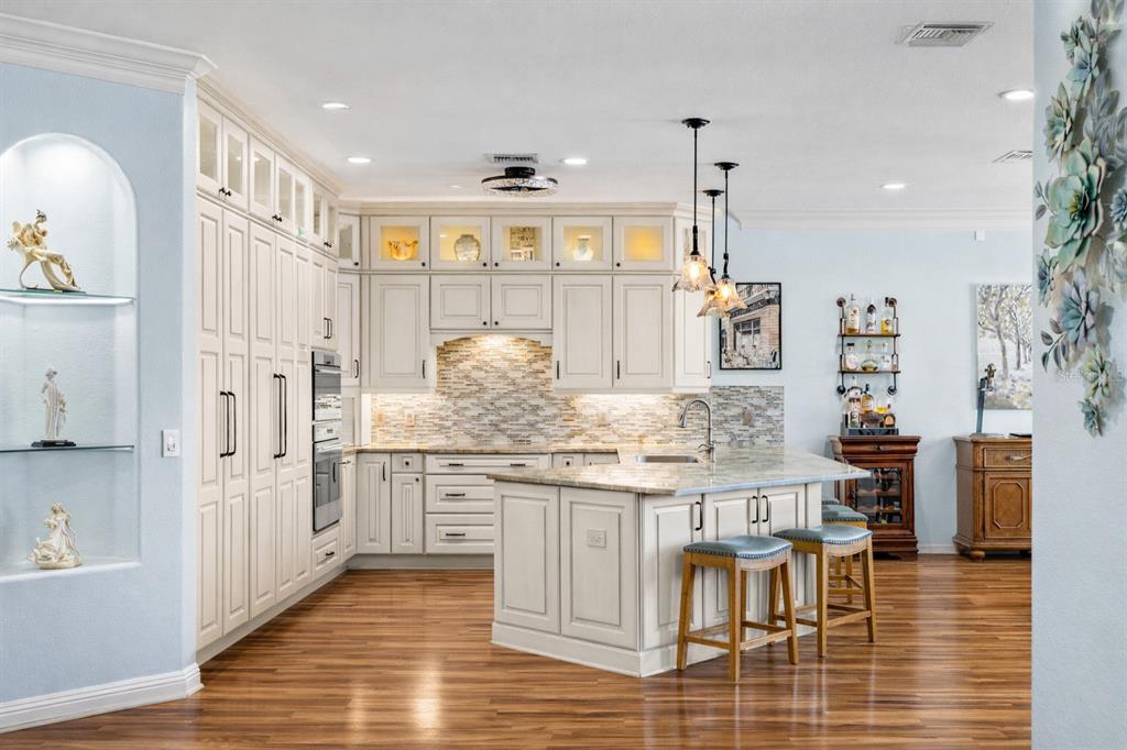 A kitchen with white cabinetry, a central island with bar stools, and hardwood flooring — 20630 DENNISPORT LANE, NORTH FORT MYERS, FL