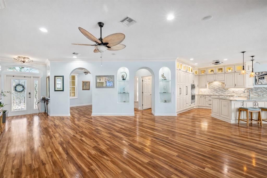 A spacious living area with hardwood floors, arched wall niches, and an open-concept kitchen — 20630 DENNISPORT LANE, NORTH FORT MYERS, FL