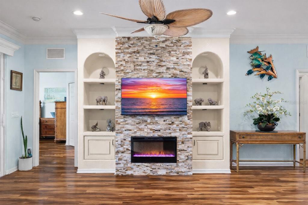 A living room features a stone fireplace, a wall-mounted television, and built-in arched shelving — 20630 DENNISPORT LANE, NORTH FORT MYERS, FL
