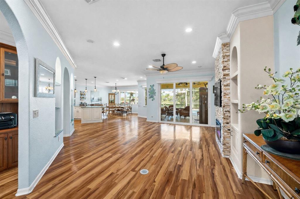 A spacious living room with hardwood floors, a stone fireplace, and views of a patio — 20630 DENNISPORT LANE, NORTH FORT MYERS, FL