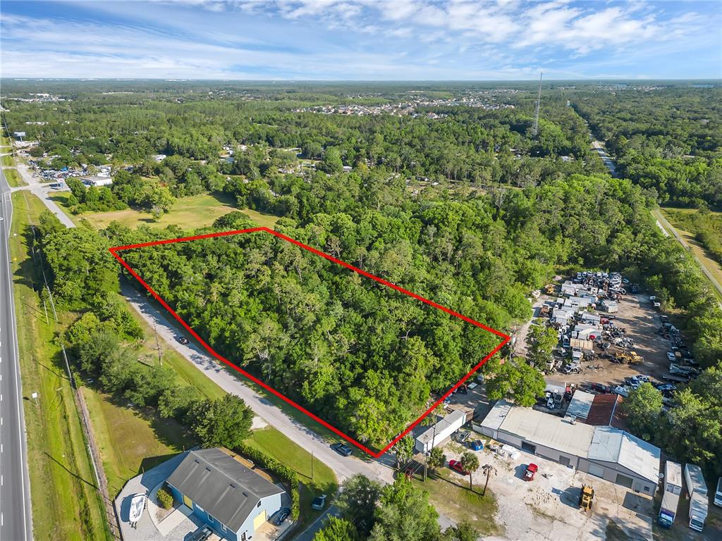 An aerial view shows a rectangular, tree-covered vacant lot outlined in red next to buildings — 502 N 5TH STREET N, ORLANDO, FL
