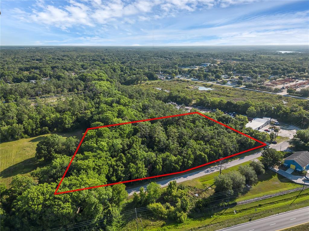 An aerial view shows a rectangular, wooded lot outlined in red next to a road — 502 N 5TH STREET N, ORLANDO, FL