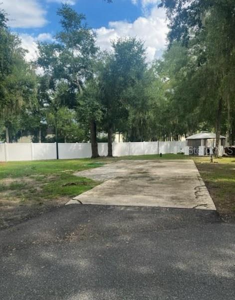 A concrete driveway pad sits in a grassy yard enclosed by a white vinyl fence — 14263 NE 252ND COURT ROAD UNIT 114, SALT SPRINGS, FL