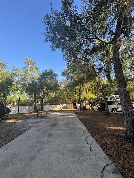 A concrete driveway leads toward a wooded area with parked vehicles and a small shed — 14263 NE 252ND COURT ROAD UNIT 114, SALT SPRINGS, FL