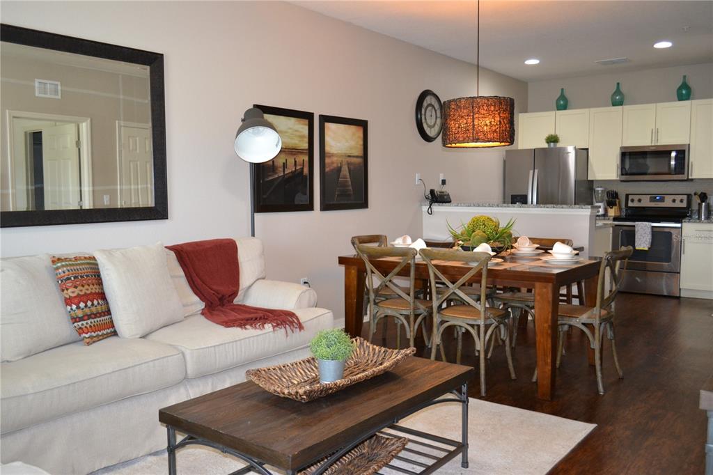 A living room and dining area feature a beige sofa, wooden coffee table, and kitchen — 3208 CUPID PLACE, KISSIMMEE, FL