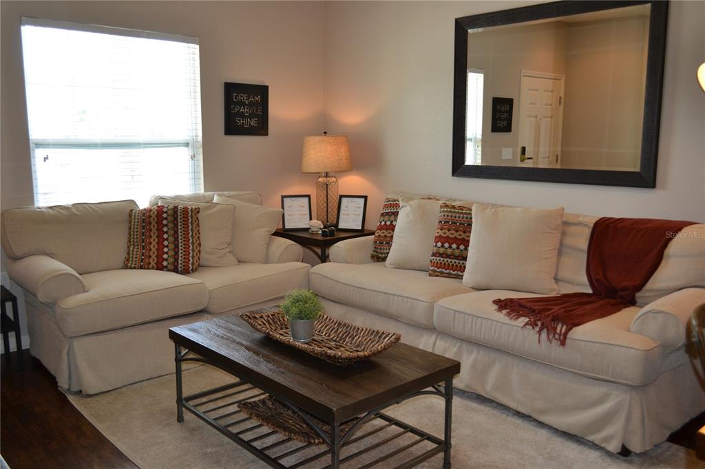A living room features two beige sofas, a wooden coffee table, and a large mirror — 3208 CUPID PLACE, KISSIMMEE, FL