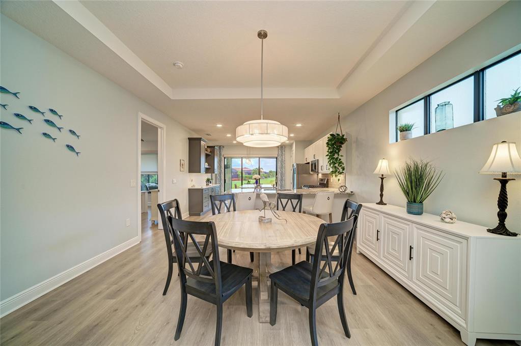 A dining room features a round wooden table, dark chairs, and a white sideboard — 5286 BARNETT CIRCLE, BRADENTON, FL