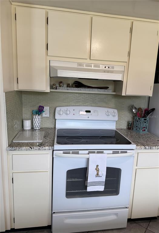 A kitchen features white cabinets, a white electric range, and granite countertops with a backsplash — 3681 GARDENIA DRIVE, INDIAN LAKE ESTATES, FL