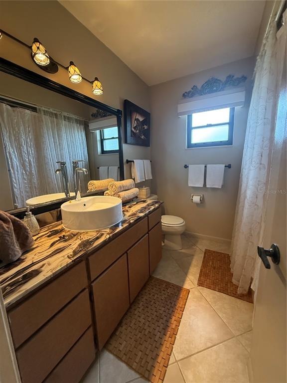A bathroom features a vessel sink on a marbled countertop, a vanity, and a shower — 3681 GARDENIA DRIVE, INDIAN LAKE ESTATES, FL