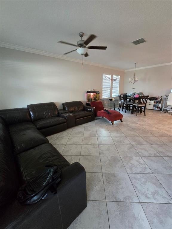 A living room with tile floors, a large black sectional sofa, and a dining area — 11436 CHILLY WATER COURT, RIVERVIEW, FL