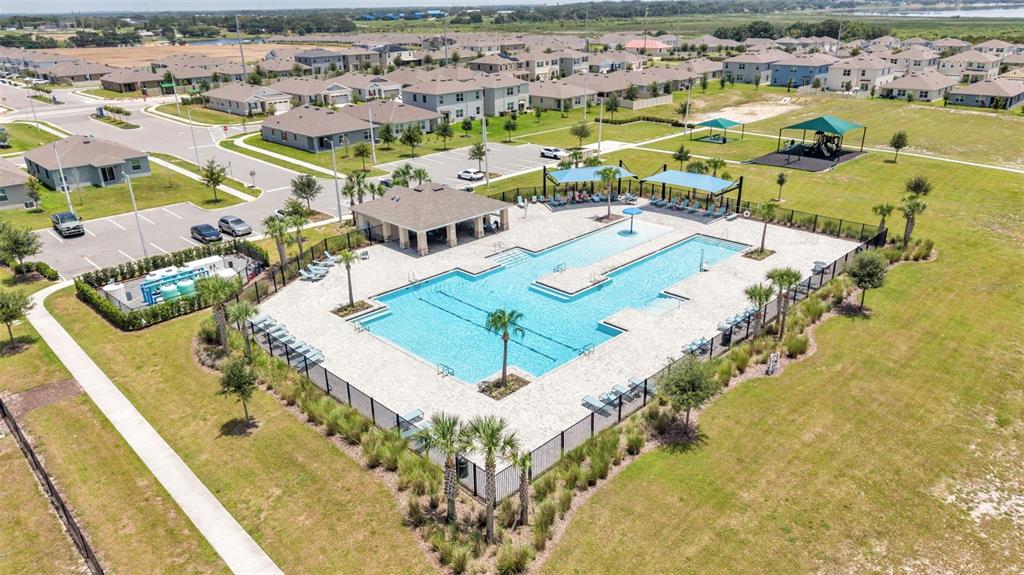 An aerial view shows a community swimming pool with a clubhouse and nearby playground — 2075 AIREDALE WAY, LAKE ALFRED, FL